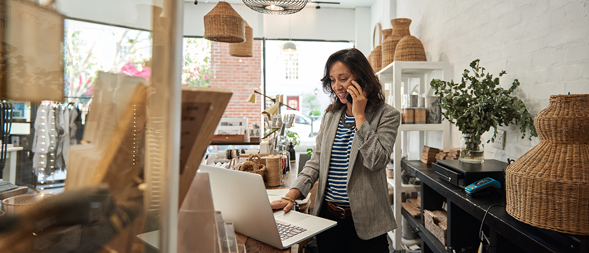 Smiling Asian woman talks with customer on phone.