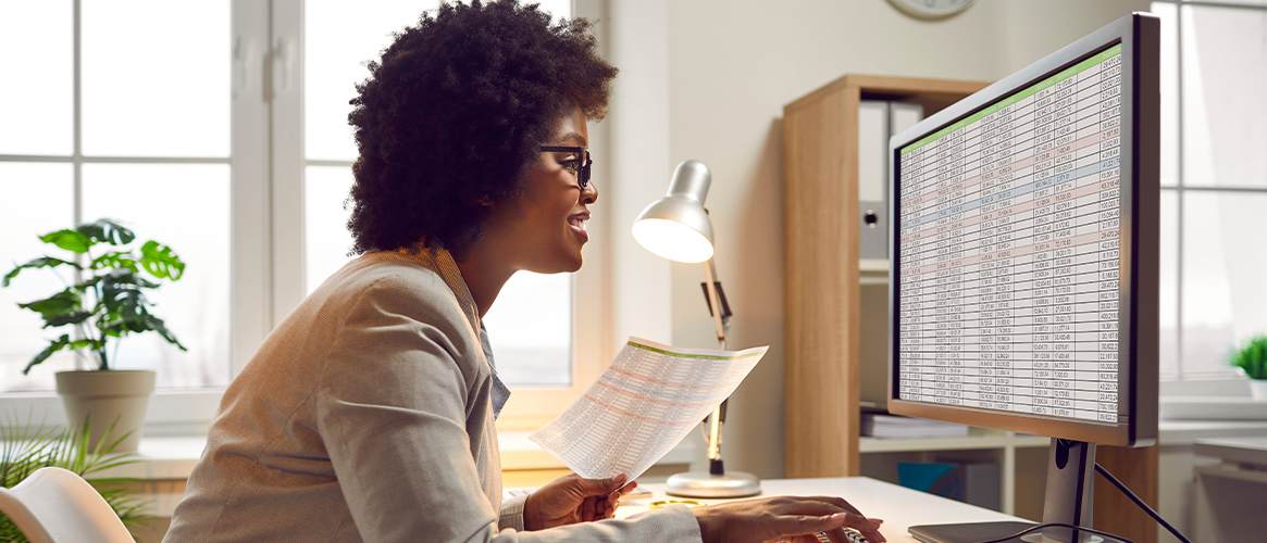 Woman looking at computer with spreadsheet program.