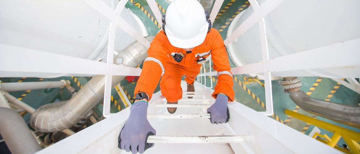 Production operator climbing up ladder to oil and gas process plant